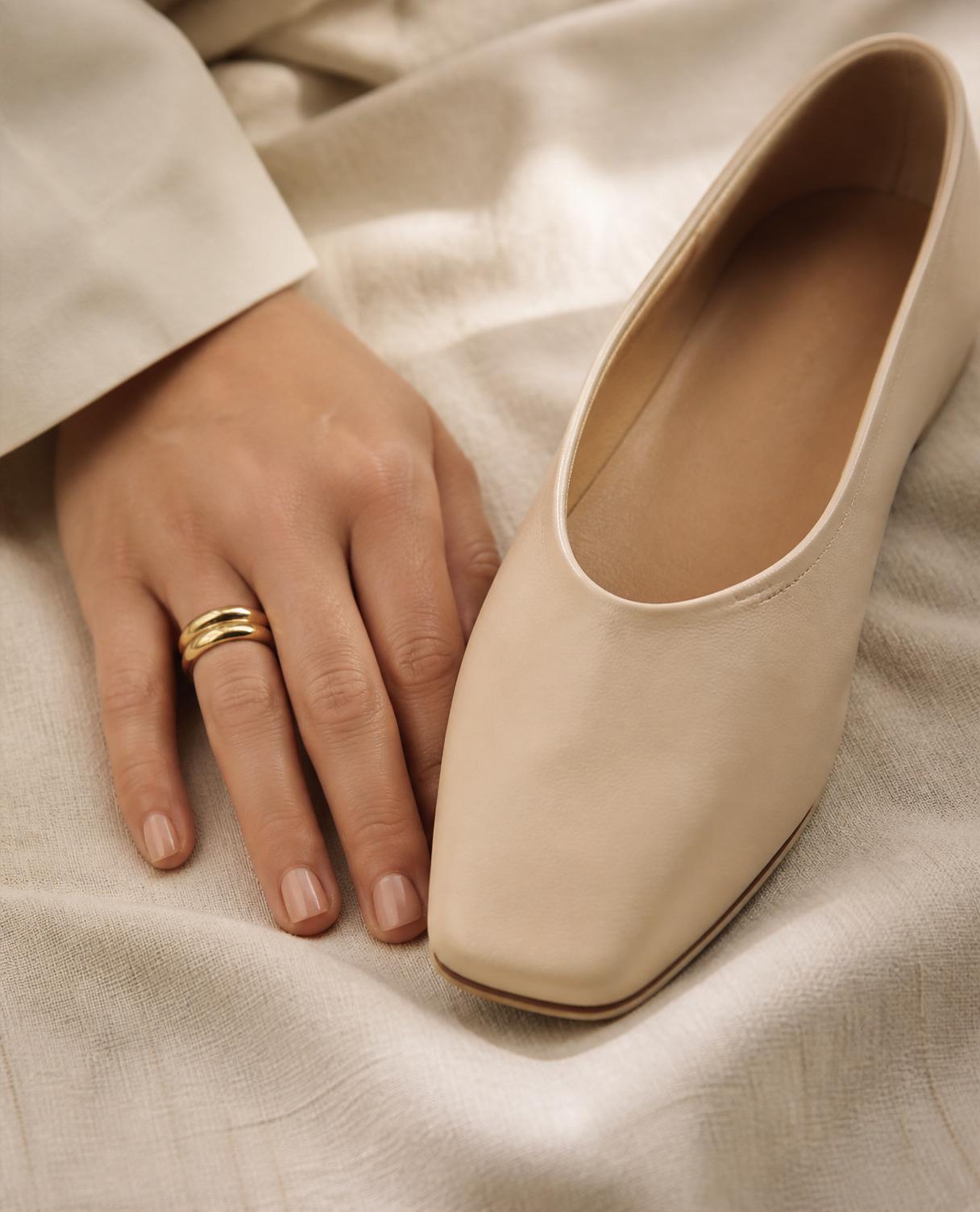 Close-up of a SHAN cream leather flat resting on soft linen, showing the fine microfiber leather finish.